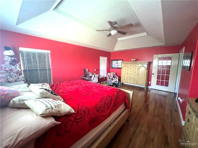 bedroom with ceiling fan, dark wood-type flooring, and a tray ceiling