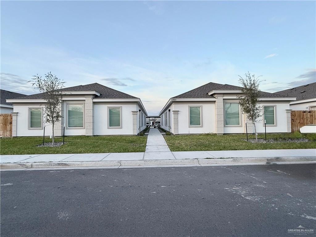 view of front of house featuring a front lawn, fence, and stucco siding