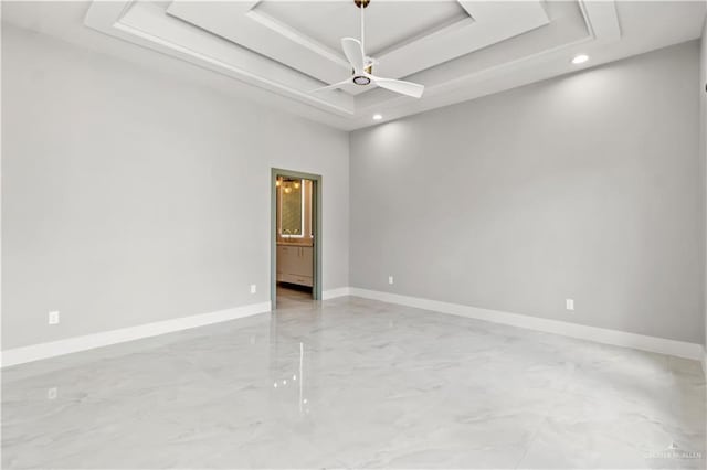 empty room featuring a tray ceiling and ceiling fan