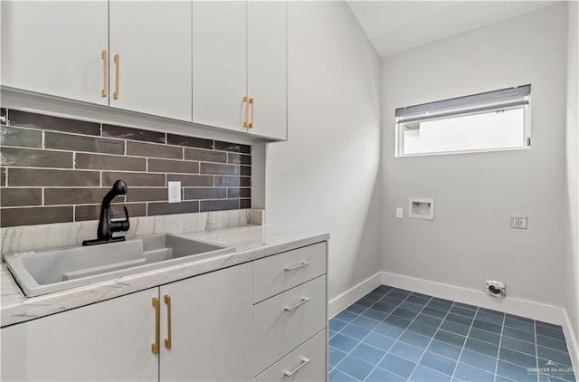 clothes washing area featuring cabinets, washer hookup, dark tile patterned flooring, and sink