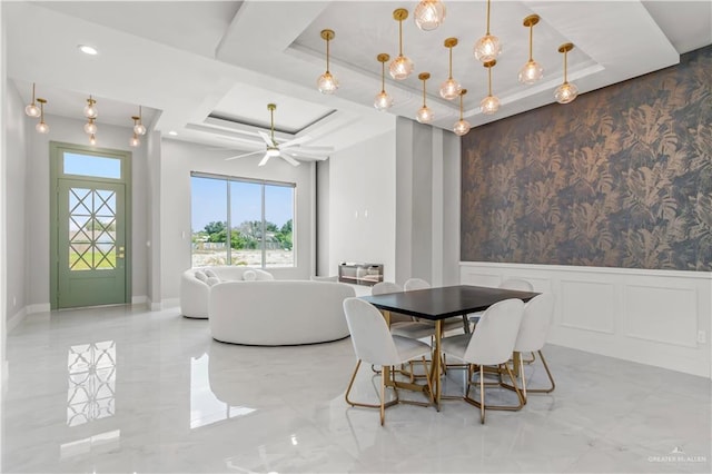 dining space featuring ceiling fan and a tray ceiling