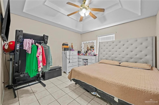 tiled bedroom featuring ceiling fan and a tray ceiling