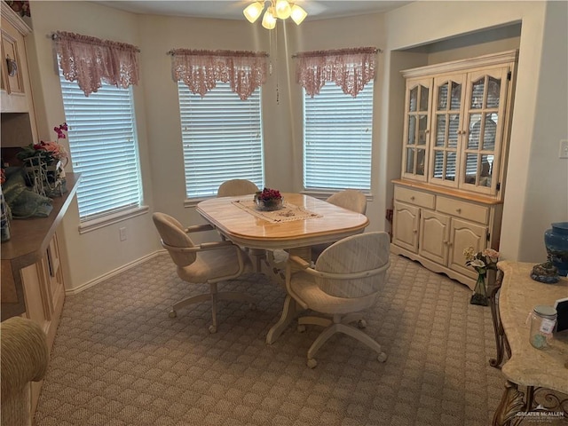 dining area with baseboards, light colored carpet, and a ceiling fan