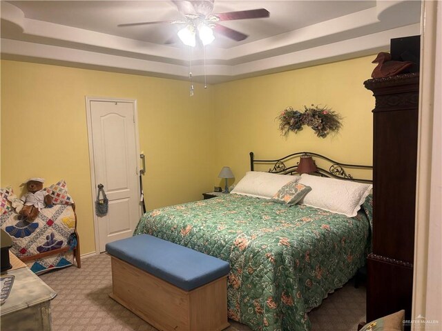 bedroom featuring a raised ceiling, carpet, and a ceiling fan
