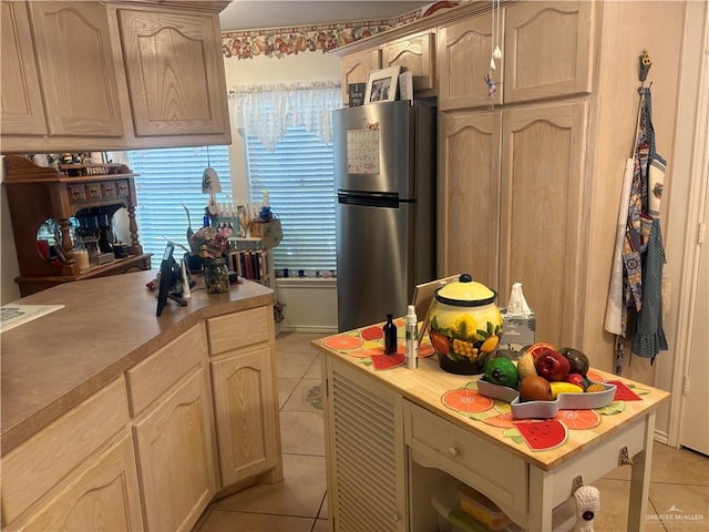 kitchen featuring light brown cabinets, light tile patterned flooring, light countertops, and freestanding refrigerator