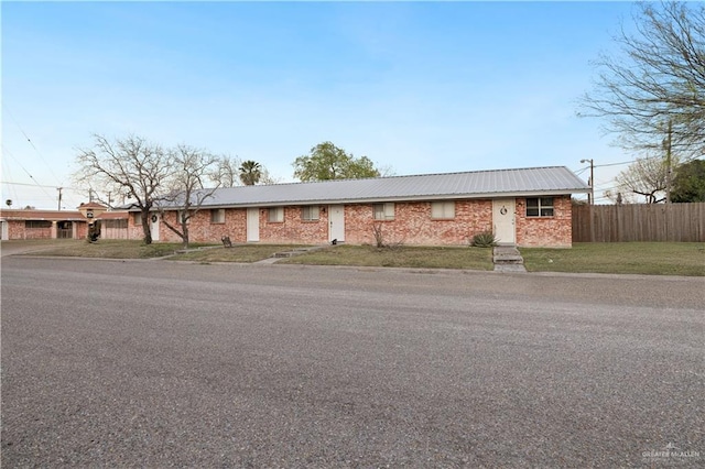 ranch-style house featuring a front lawn, fence, and brick siding