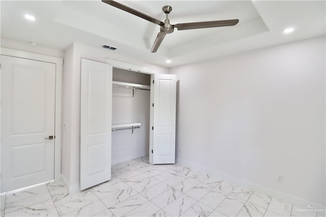 unfurnished bedroom featuring ceiling fan and a tray ceiling