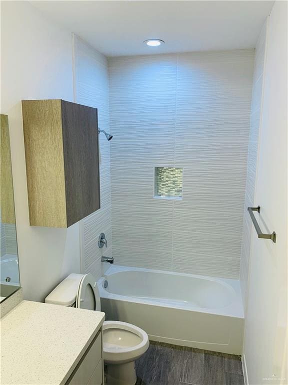 full bathroom featuring tiled shower / bath, hardwood / wood-style flooring, vanity, and toilet