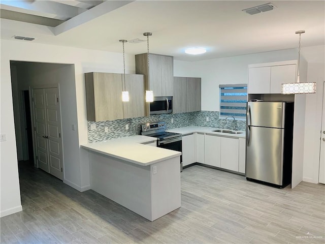 kitchen with decorative light fixtures, white cabinetry, sink, and appliances with stainless steel finishes