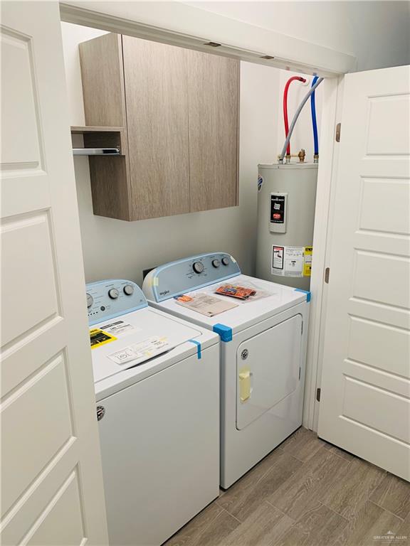 clothes washing area featuring independent washer and dryer, water heater, and light wood-type flooring