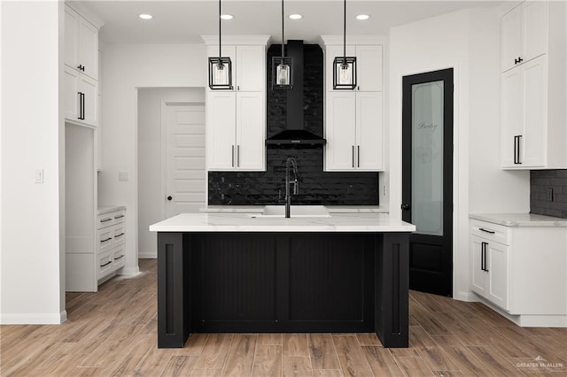 kitchen with pendant lighting, a center island with sink, and white cabinets