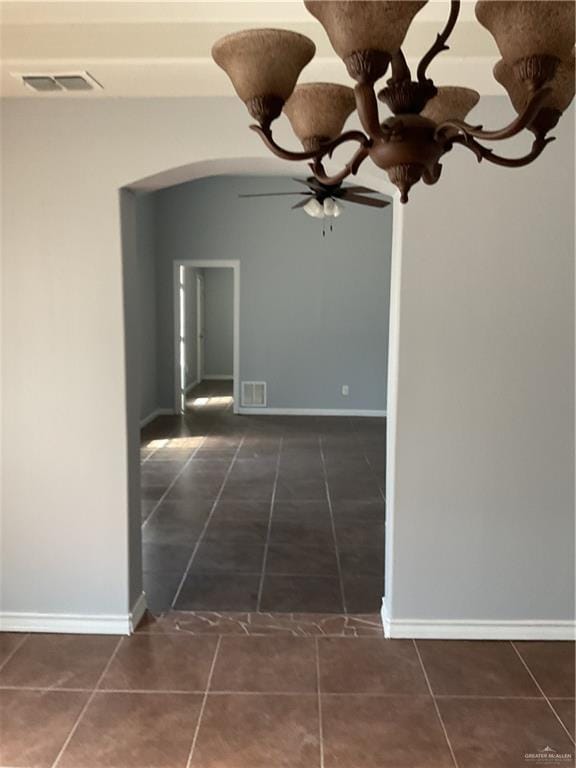 hall with tile patterned floors, visible vents, arched walkways, and baseboards