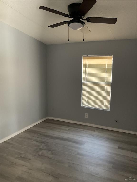 empty room with baseboards, wood finished floors, and a ceiling fan