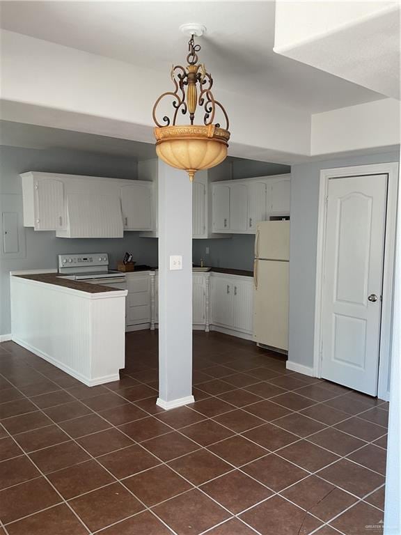 kitchen featuring white appliances, white cabinets, dark countertops, and a peninsula