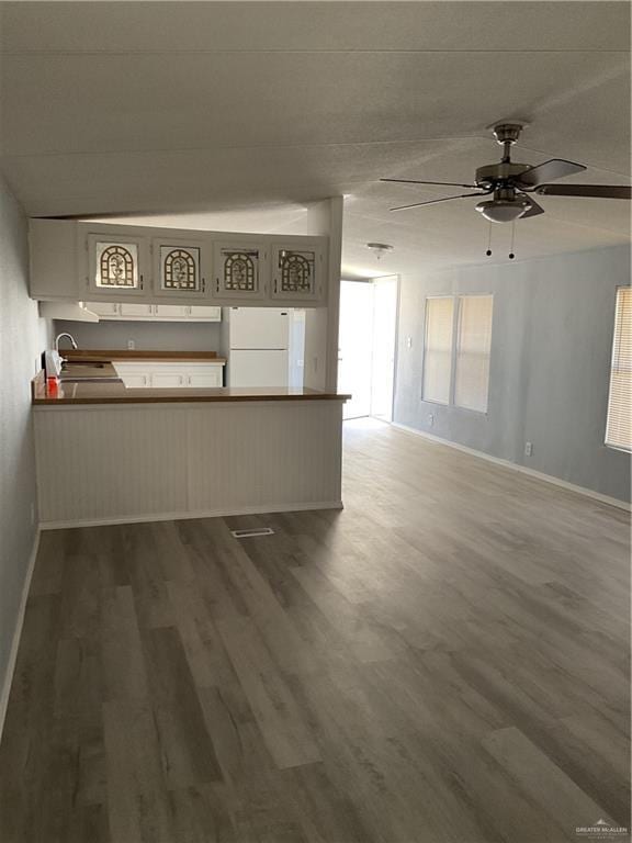 unfurnished living room with baseboards, ceiling fan, and wood finished floors