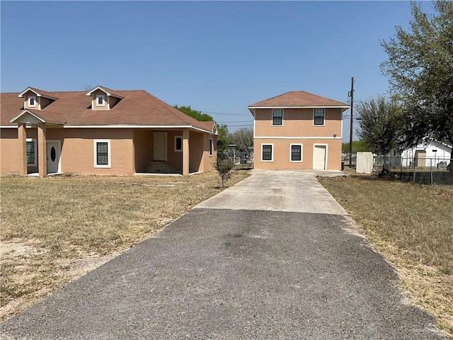 view of front of property featuring fence, driveway, and stucco siding