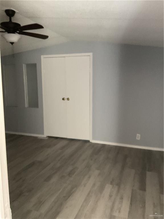 unfurnished room with baseboards, wood finished floors, lofted ceiling, and ceiling fan