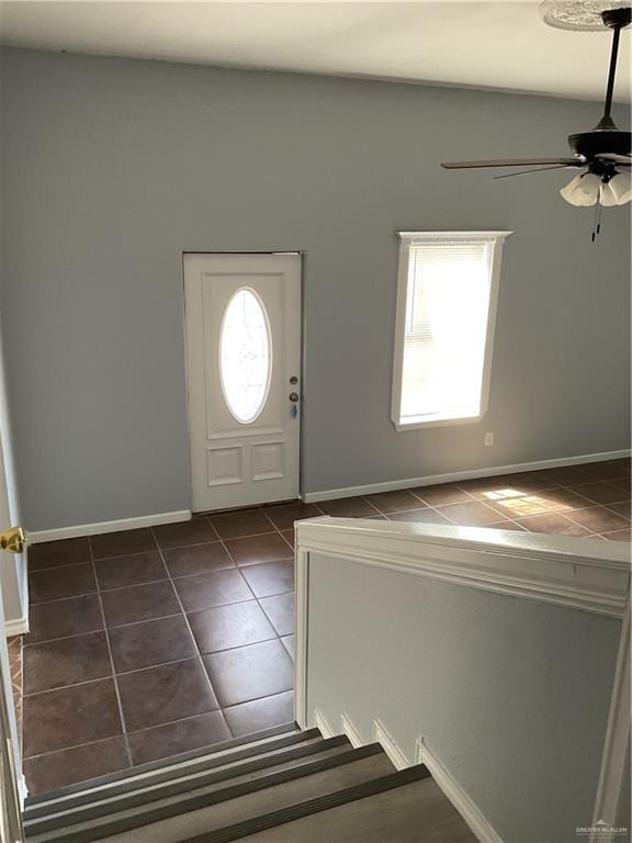 entryway with dark tile patterned floors, baseboards, and ceiling fan