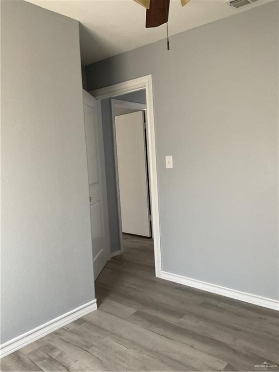 empty room featuring wood finished floors, a ceiling fan, and baseboards