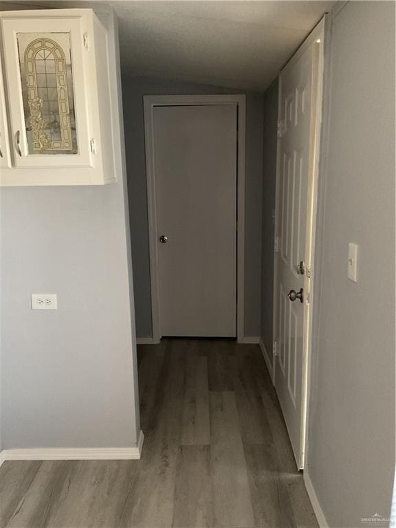 corridor with baseboards and wood finished floors