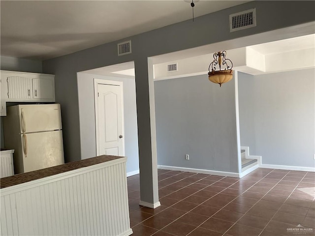 interior space with visible vents, freestanding refrigerator, and baseboards