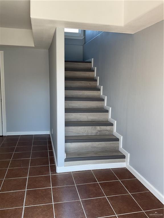 staircase featuring tile patterned floors and baseboards