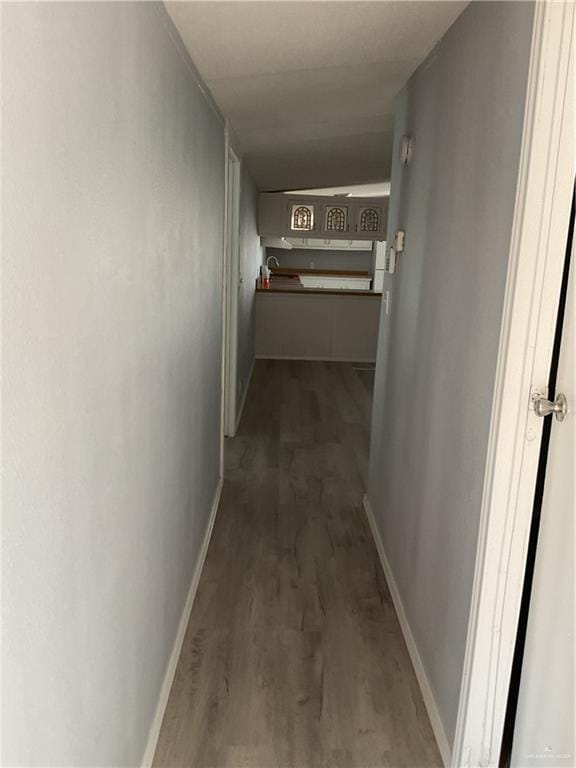 hallway with baseboards and dark wood-style flooring