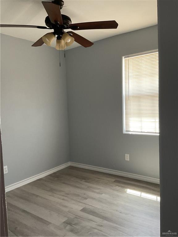 unfurnished room featuring baseboards, wood finished floors, and a ceiling fan