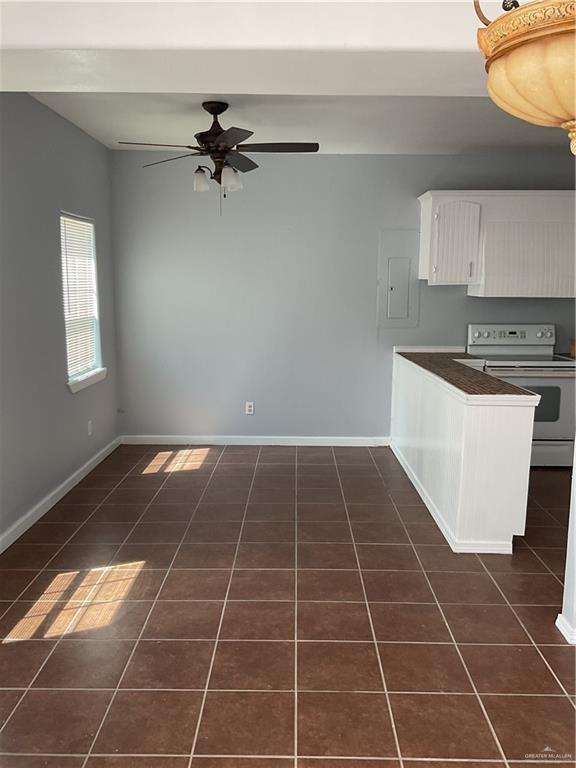 kitchen featuring white electric range oven, a ceiling fan, white cabinetry, dark countertops, and dark tile patterned floors