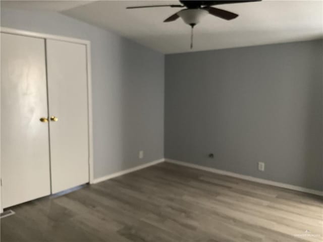 unfurnished bedroom featuring ceiling fan, a closet, baseboards, and wood finished floors