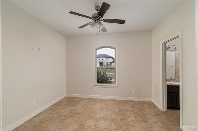 empty room with a sink, a ceiling fan, and baseboards