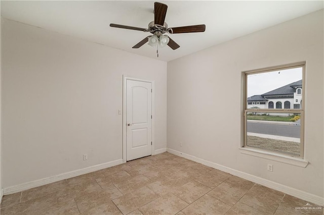 empty room featuring ceiling fan and baseboards