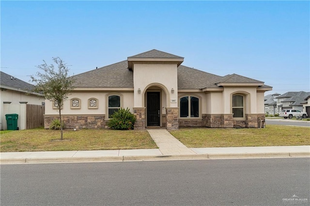 view of front of home featuring roof with shingles, stucco siding, a front yard, fence, and stone siding