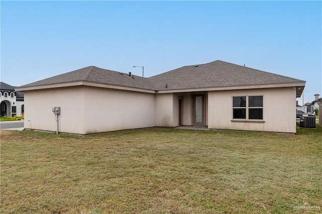 rear view of property with cooling unit, roof with shingles, and a lawn