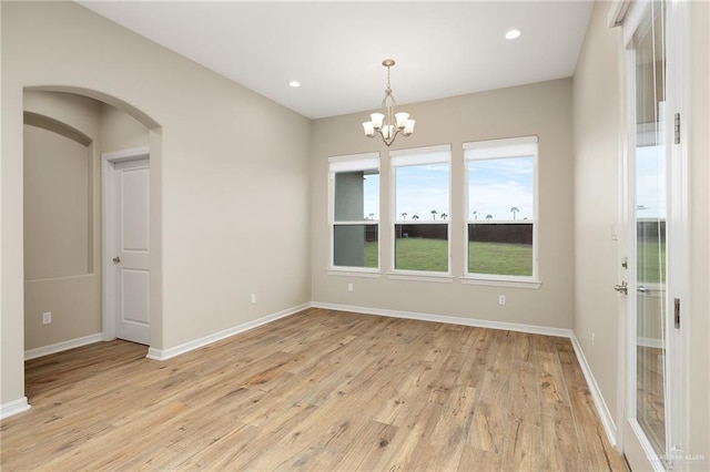 empty room with a chandelier and light hardwood / wood-style flooring