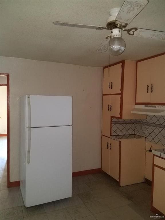 kitchen featuring cream cabinetry, ceiling fan, and white fridge