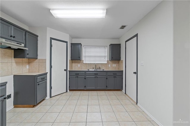 3017 Paradise Ave, Harlingen, TX 78552 - kitchen with under cabinet range hood, gray cabinets, backsplash, and light countertops