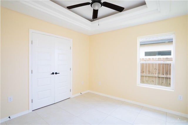 unfurnished bedroom featuring light tile patterned floors, a closet, a raised ceiling, and ceiling fan