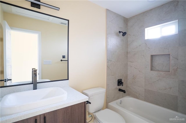 full bathroom featuring vanity, tiled shower / bath combo, and toilet