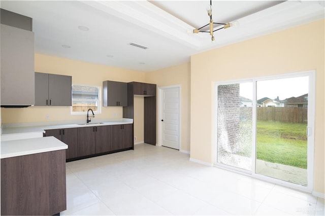 kitchen with dark brown cabinetry, sink, light tile patterned floors, and a chandelier