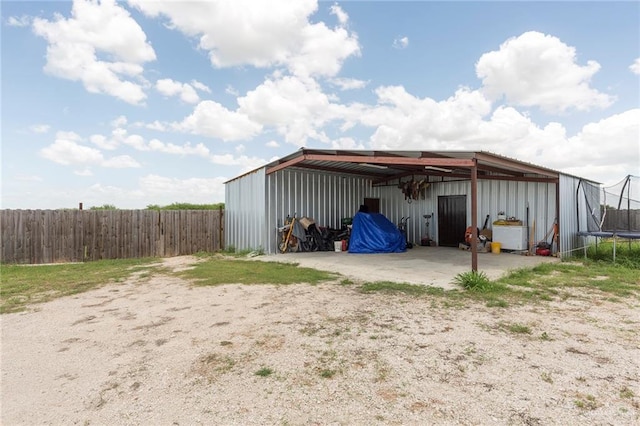 view of pole building with a trampoline and fence