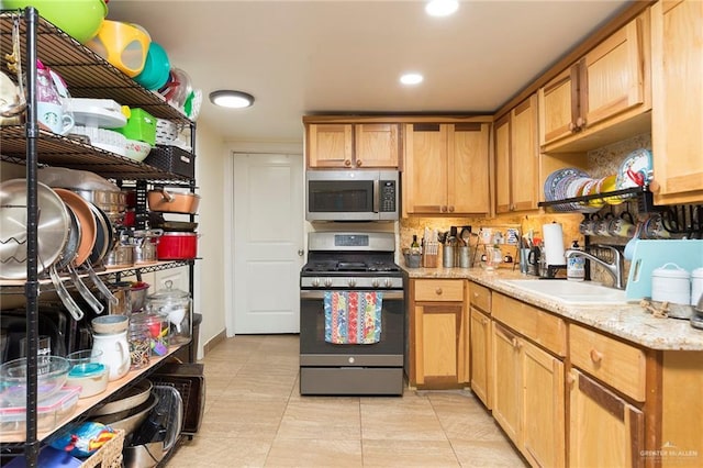 kitchen featuring light tile patterned floors, light stone countertops, stainless steel appliances, a sink, and recessed lighting