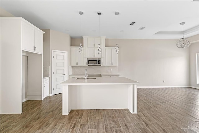 kitchen with hardwood / wood-style flooring, pendant lighting, sink, and an island with sink