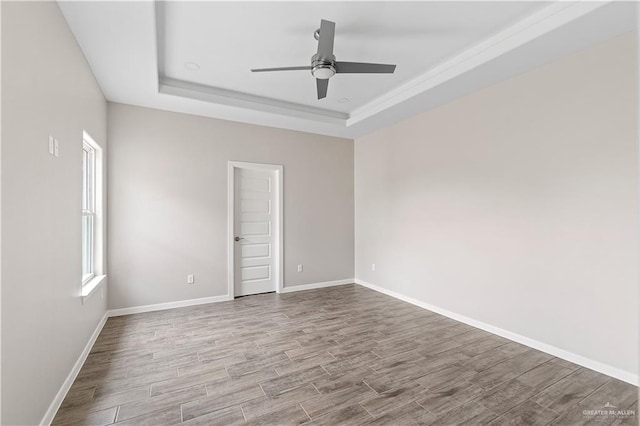 unfurnished room with a raised ceiling, ceiling fan, and light hardwood / wood-style floors