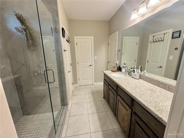 bathroom with a shower with door, vanity, and tile patterned flooring