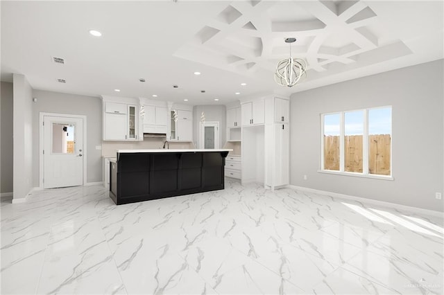 kitchen featuring a center island with sink, a notable chandelier, white cabinets, pendant lighting, and coffered ceiling