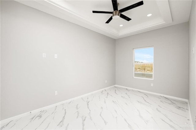 unfurnished room with ceiling fan and a tray ceiling