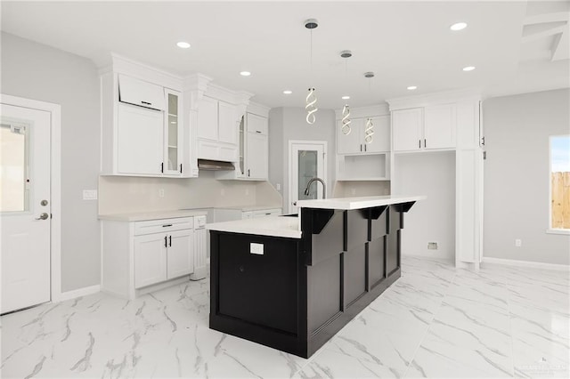 kitchen with an island with sink, sink, white cabinetry, and decorative light fixtures