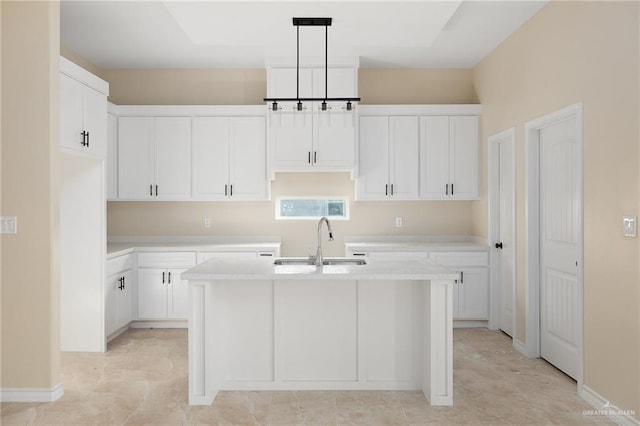 kitchen with pendant lighting, white cabinetry, sink, and an island with sink