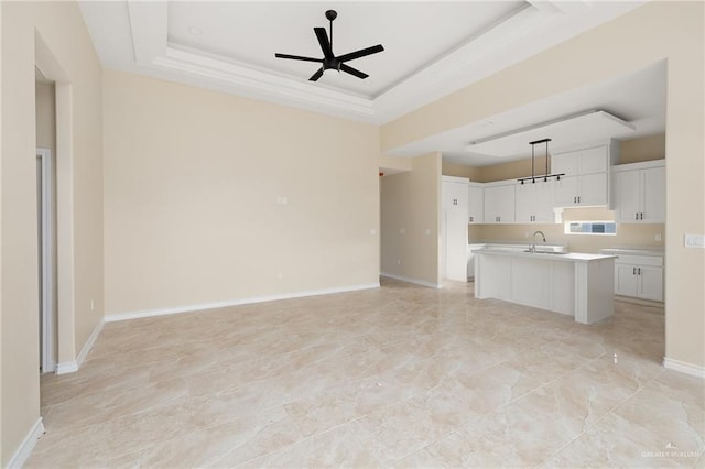 unfurnished living room with ceiling fan, a raised ceiling, and sink